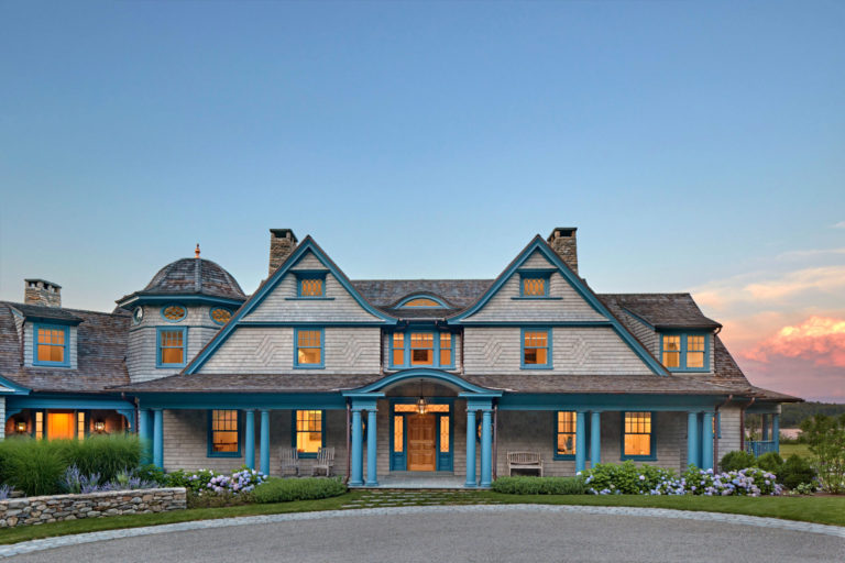 A large blue house with a spacious driveway leading up to its entrance