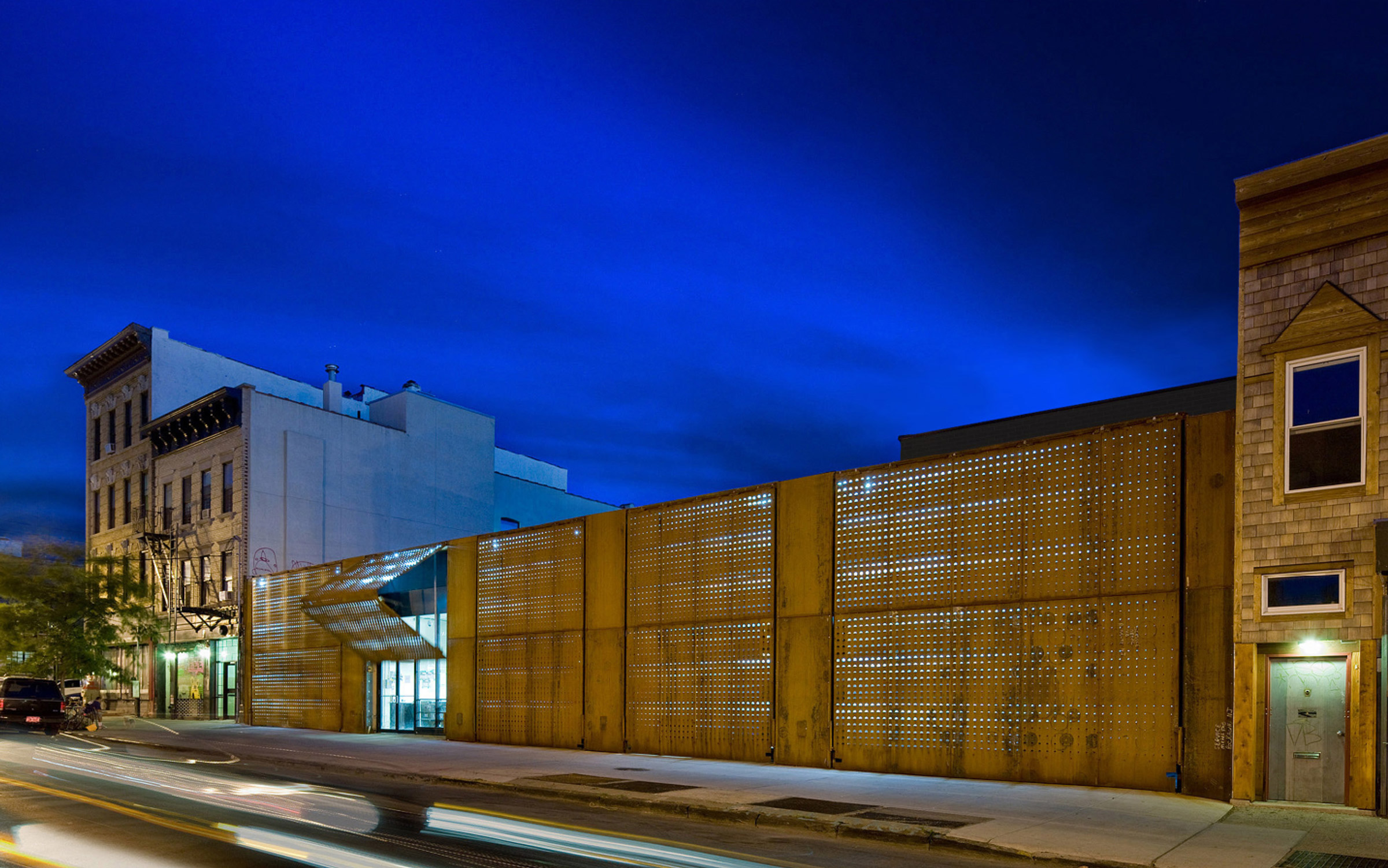 A nighttime view of a building with a wooden fence